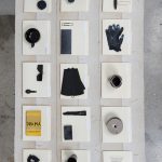 Amanda Ross-Ho and Diedrick Brackens. <em>Untitled Floor Arrangement (DRAMA)</em>, 2017. Handwoven cotton rugs, manilla folders, sensitive documents, labels, lint roller, black nitrile gloves, black vase, double fold bias tape (roll), ice scraper, plastic salsa bowl, oversized black paper clip, vinyl letters, material test with oversized black paper clip, material test with binder clip, camera case, three black owl glasses origin unknown, staple remover, satin seam binding, yarn ball, black mug, sunglasses, measuring spoon, DRAMA book, black scrunchie, and material test with oversized gold paper clip, 11 1/2 x 81 x 44 inches