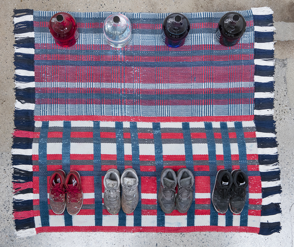 Amanda Ross-Ho and Diedrick Brackens. <em>Untitled Floor Arrangement (300 bucks would save my life)</em>, 2017. Handwoven cotton rugs, glass jugs, Procion dyes, Nike Dunks, and Reebok Pumps, 12 1/4 x 64 1/2 x 48 inches