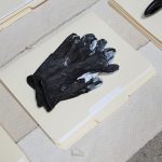 Amanda Ross-Ho and Diedrick Brackens. <em>Untitled Floor Arrangement (DRAMA)</em>, 2017. Handwoven cotton rugs, manilla folders, sensitive documents, labels, lint roller, black nitrile gloves, black vase, double fold bias tape (roll), ice scraper, plastic salsa bowl, oversized black paper clip, vinyl letters, material test with oversized black paper clip, material test with binder clip, camera case, three black owl glasses origin unknown, staple remover, satin seam binding, yarn ball, black mug, sunglasses, measuring spoon, DRAMA book, black scrunchie, and material test with oversized gold paper clip, 11 1/2 x 81 x 44 inches. Detail