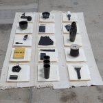 Amanda Ross-Ho and Diedrick Brackens. <em>Untitled Floor Arrangement (DRAMA)</em>, 2017. Handwoven cotton rugs, manilla folders, sensitive documents, labels, lint roller, black nitrile gloves, black vase, double fold bias tape (roll), ice scraper, plastic salsa bowl, oversized black paper clip, vinyl letters, material test with oversized black paper clip, material test with binder clip, camera case, three black owl glasses origin unknown, staple remover, satin seam binding, yarn ball, black mug, sunglasses, measuring spoon, DRAMA book, black scrunchie, and material test with oversized gold paper clip, 11 1/2 x 81 x 44 inches