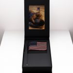<em>South Body</em>, 2019. Artist presentation box, usb drive, 18 x 11.96 cm photograph, American flag with 14K gold tip, 2 3/4 x 7 7/8 x 11 3/4 inches (7 x 20 x 30 cm)