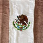 <em>Insignia V</em>, 2023. Satin and blood of Mexican women, 35 3/8 x  5/8 inches (90 x 1.6 cm)