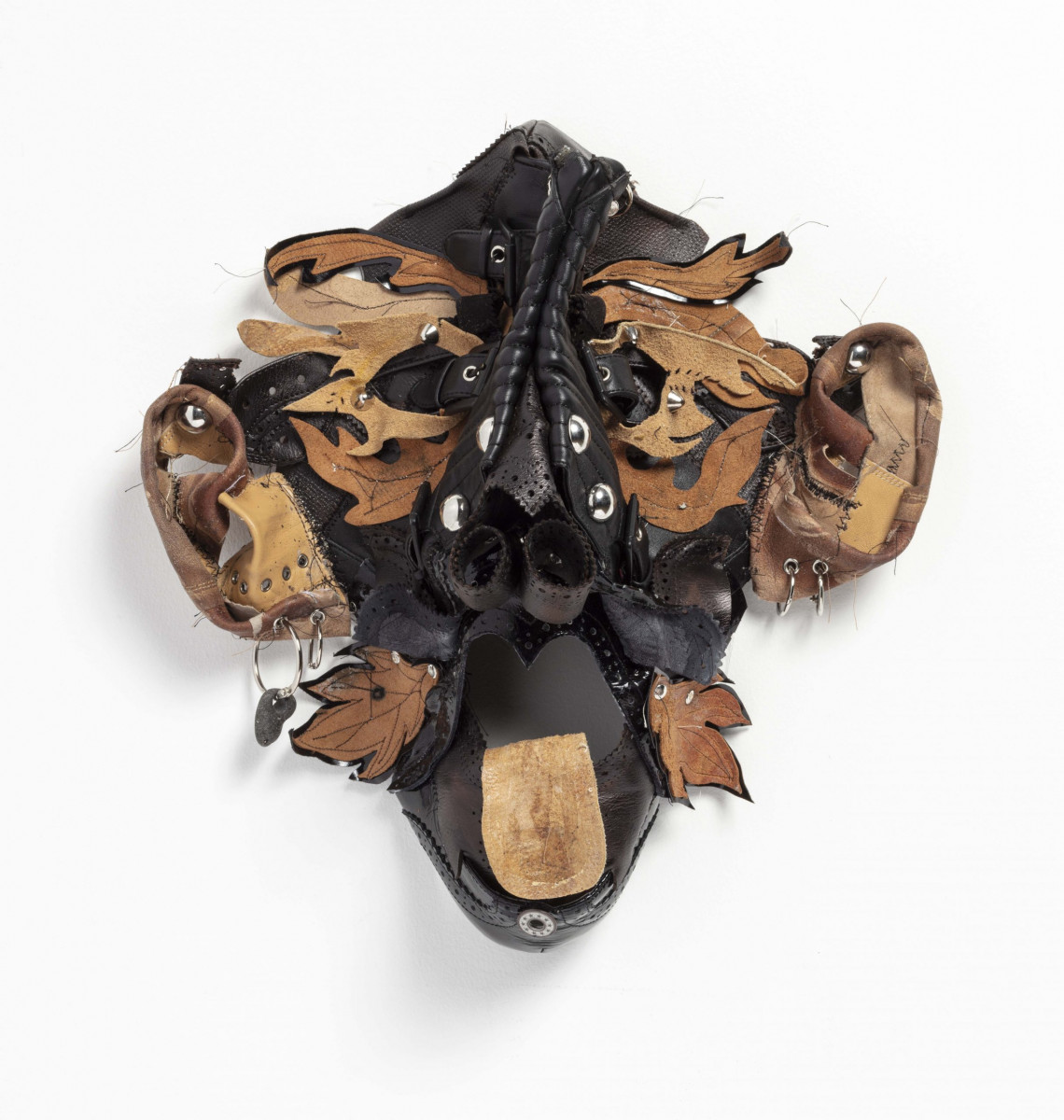 Jakob Rowlinson. <em>Mask XI</em>, 2023. Leather, PVC, buckles, split rings, eyelets, split pins, hag stone and rivets, 14 x 14 x 5 1/2 inches (35.6 x 35.6 x 14 cm)